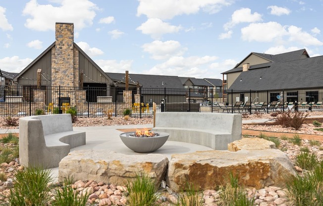 a patio with chairs and a fire pit in front of a building