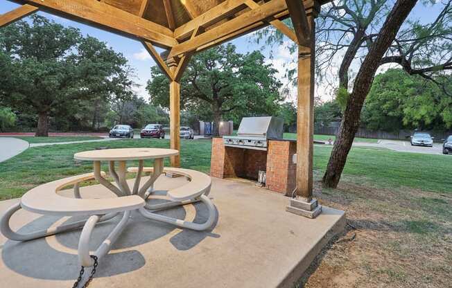 a patio with a table and a grill in a park