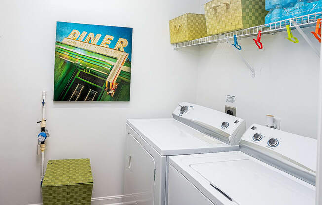 a laundry room with two washing machines and a painting on the wall