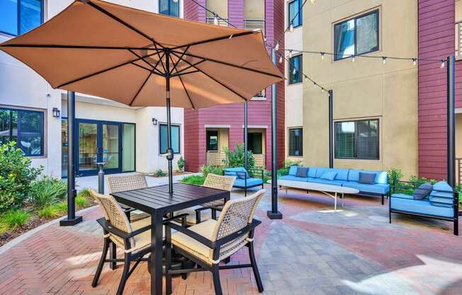 A patio with a table and chairs under an umbrella.