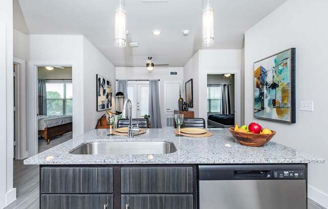A modern kitchen with a granite countertop and stainless steel appliances.
