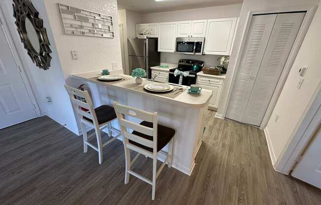 A kitchen with white cabinets and a wooden floor.