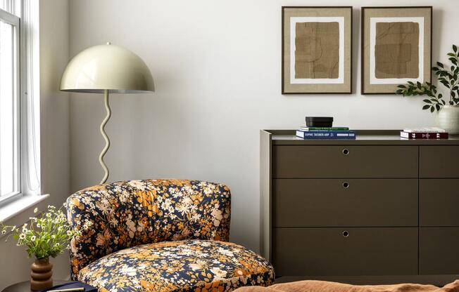 a bedroom with a chair and a lamp and a dresser