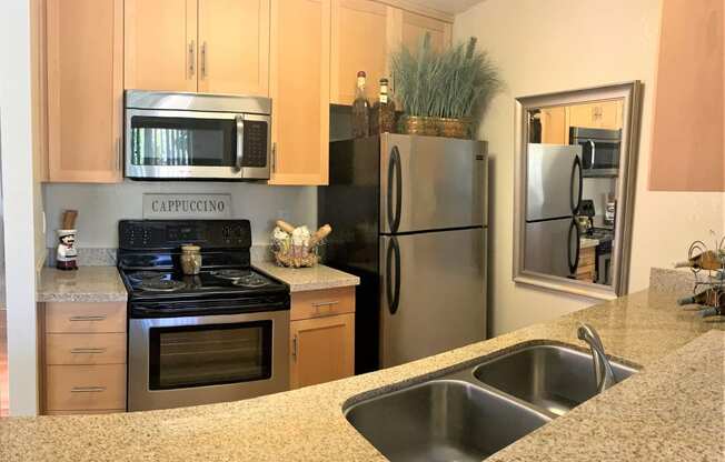 2 bedroom model  kitchen with black/stainless steel appliances such as refrigerator, microwave and stove/oven