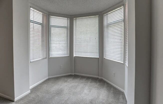 an empty room with three windows and a carpeted floor