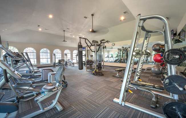 A gym with a variety of equipment including treadmills, weights, and exercise machines.