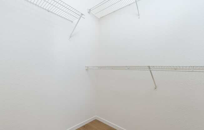 a room with white walls and a white closet and a wire rack on the wall