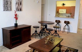 A room with a wooden cabinet, a table with a vase of flowers, and a mirror on the wall.