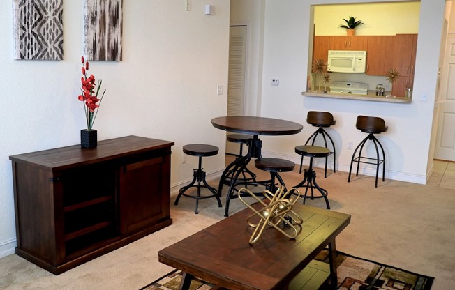 A room with a wooden cabinet, a table with a vase of flowers, and a mirror on the wall.