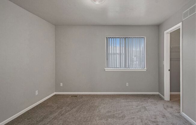 an empty living room with a window and carpet