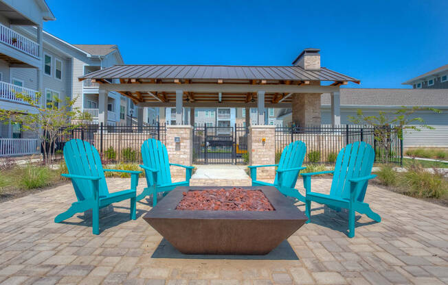 a firepit with blue adirondack chairs sits in the middle of a brick patio