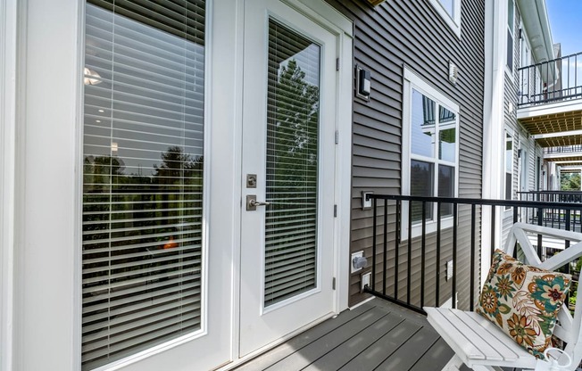 A white door with a window above it and a balcony to the right.