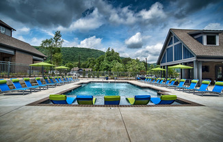 a swimming pool with blue and yellow lounge chairs around it