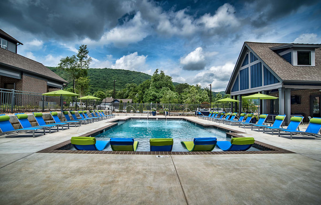 a swimming pool with blue and yellow lounge chairs around it