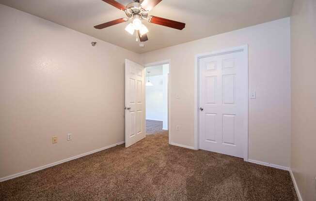 Bedroom with carpet, door, and ceiling fan