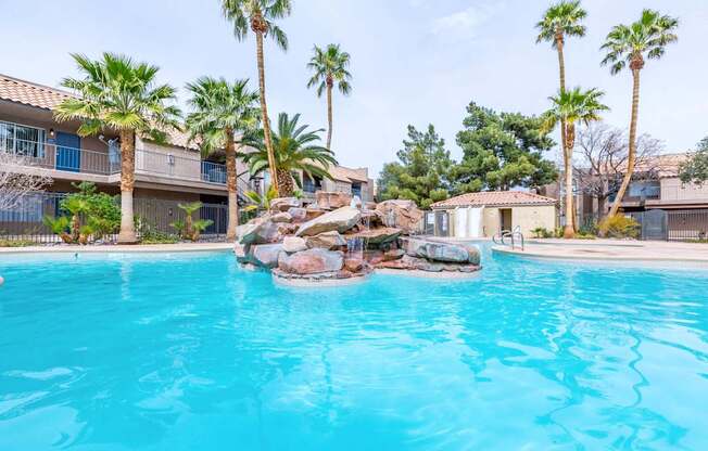 A swimming pool surrounded by palm trees and rocks.