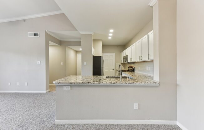 A kitchen area with a granite countertop and white cabinets.