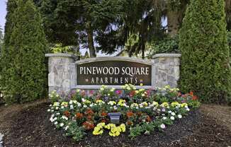 Stone Welcome Sign to Pinewood Square Apartment Homes with Flower Bed Below at Pinewood Square Apartment Homes, WA 98087