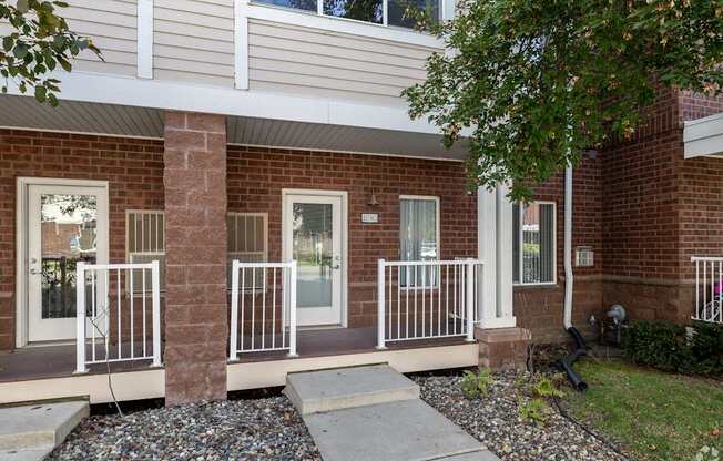 A brick house with a white door and a white railing.
