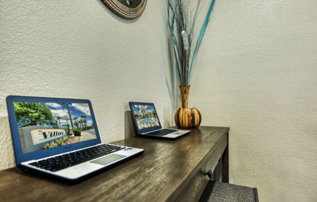 two laptop computers sitting on a wooden desk at Villas on Bell, Arizona