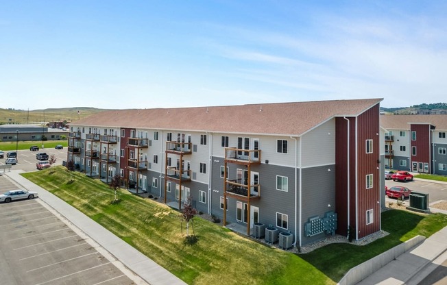 an aerial view of an apartment building with a parking lot and grass