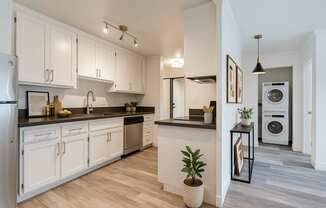 A modern kitchen with white cabinets and a wooden floor.