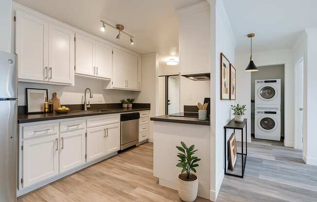 A modern kitchen with white cabinets and a wooden floor.