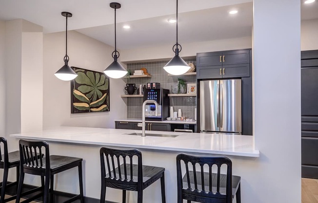 A kitchen with a white counter and black chairs.