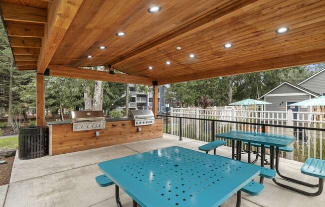 a covered patio with picnic tables and a barbecue grill