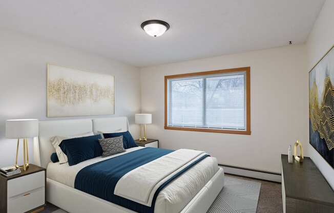 a bedroom with a white bed and a blue and white comforter. Fargo, ND Windsor Apartments