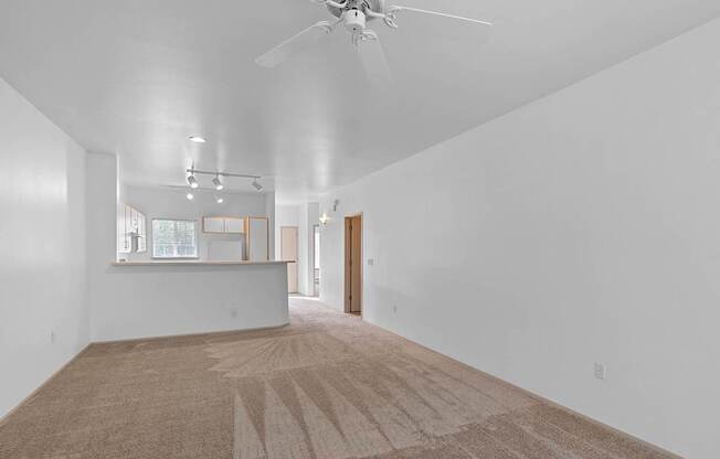 a living room with white walls and a ceiling fan