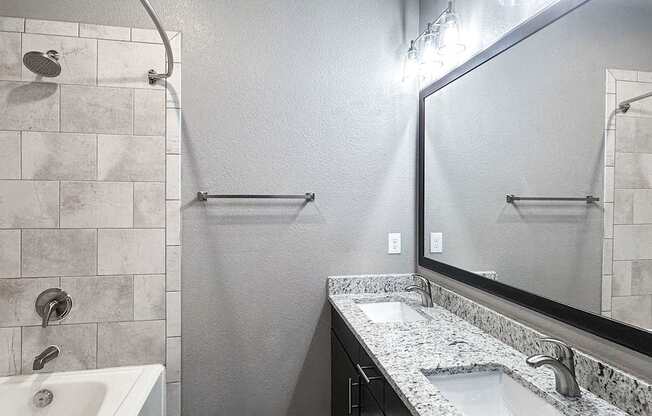 Townhome bathroom with granite countertops, dual vanities and framed mirror