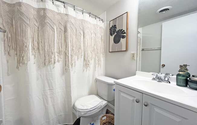 a bathroom with a white sink and toilet and a white shower curtain