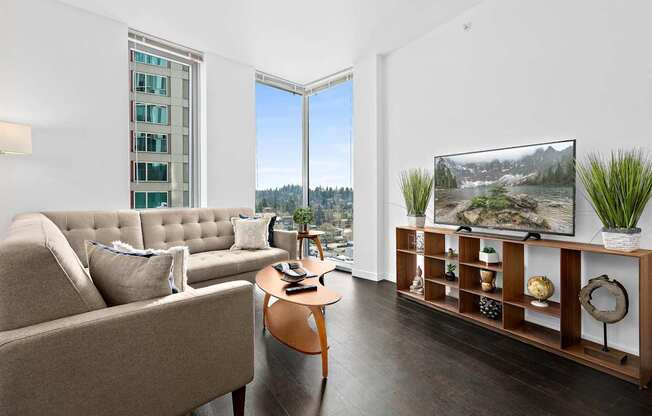 A living room with a couch, a coffee table, and a large window overlooking a forest.