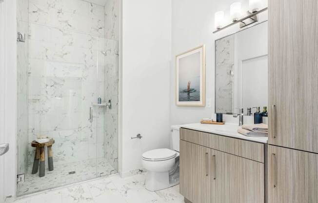 A bathroom with a toilet, sink, and a picture of a boat on the wall.