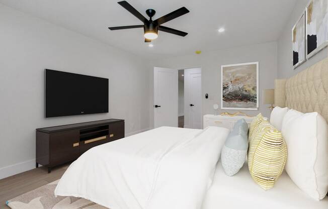 a bedroom with a large white bed and a ceiling fan