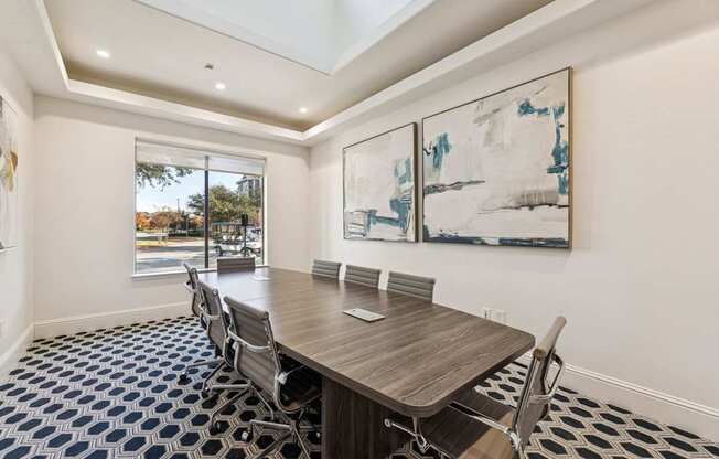 A dining room with a table and chairs and a painting on the wall.