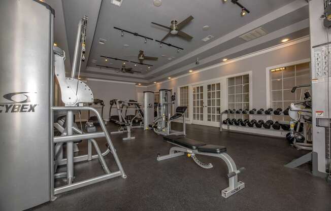 A gym with a variety of equipment including a weight bench, a leg press machine, and a squat rack.