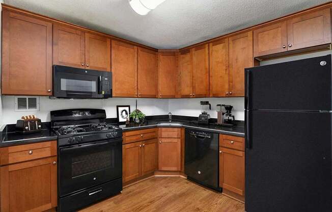 A kitchen with black appliances and wooden cabinets.