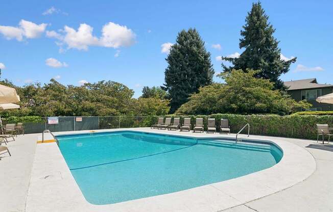 A large outdoor swimming pool surrounded by trees and a fence.