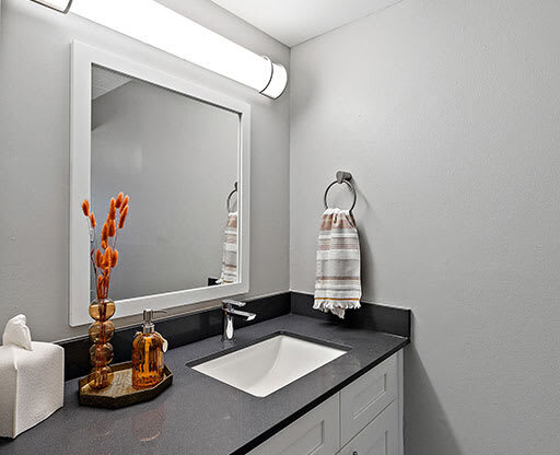 A bathroom with a sink, mirror, and towel rack.