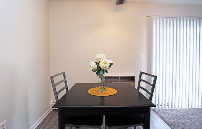 a dining room with a table and chairs and a vase of flowers