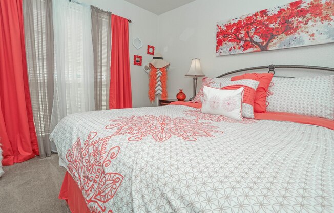A bed with a white comforter and red pillows in our model apartment at Laurel Parc apartments in Shreveport, LA.