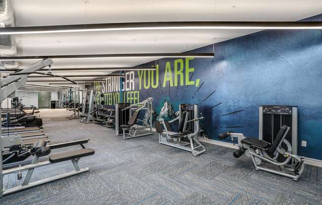 a gym with cardio machines and a wall with you are what you are