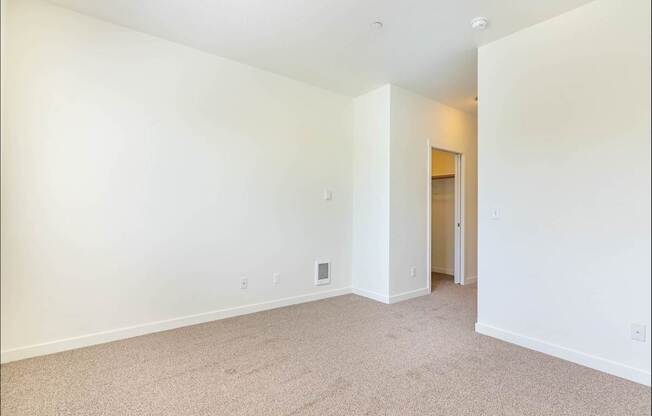 A large, empty room with carpeted flooring and white walls at Riverplace Apartment Homes, Oregon