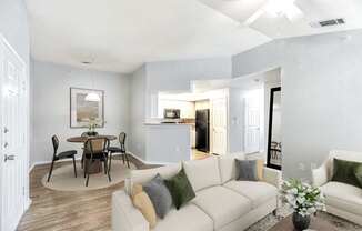 A living room with a white couch and a dining table.