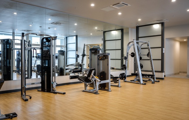 a gym with cardio equipment and weights on a wooden floor