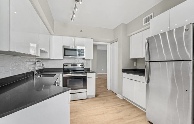 a modern kitchen with stainless steel appliances and white cabinets