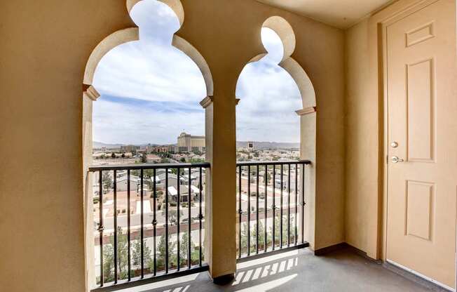 A balcony with a view of a cityscape through arched windows.