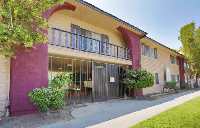 a yellow building with a red and yellow wall and a black gate in front of it